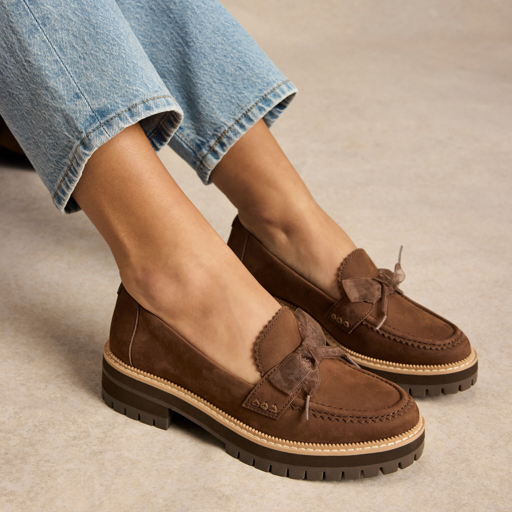 On model image of the cocoa brown Cara loafer with bow detail