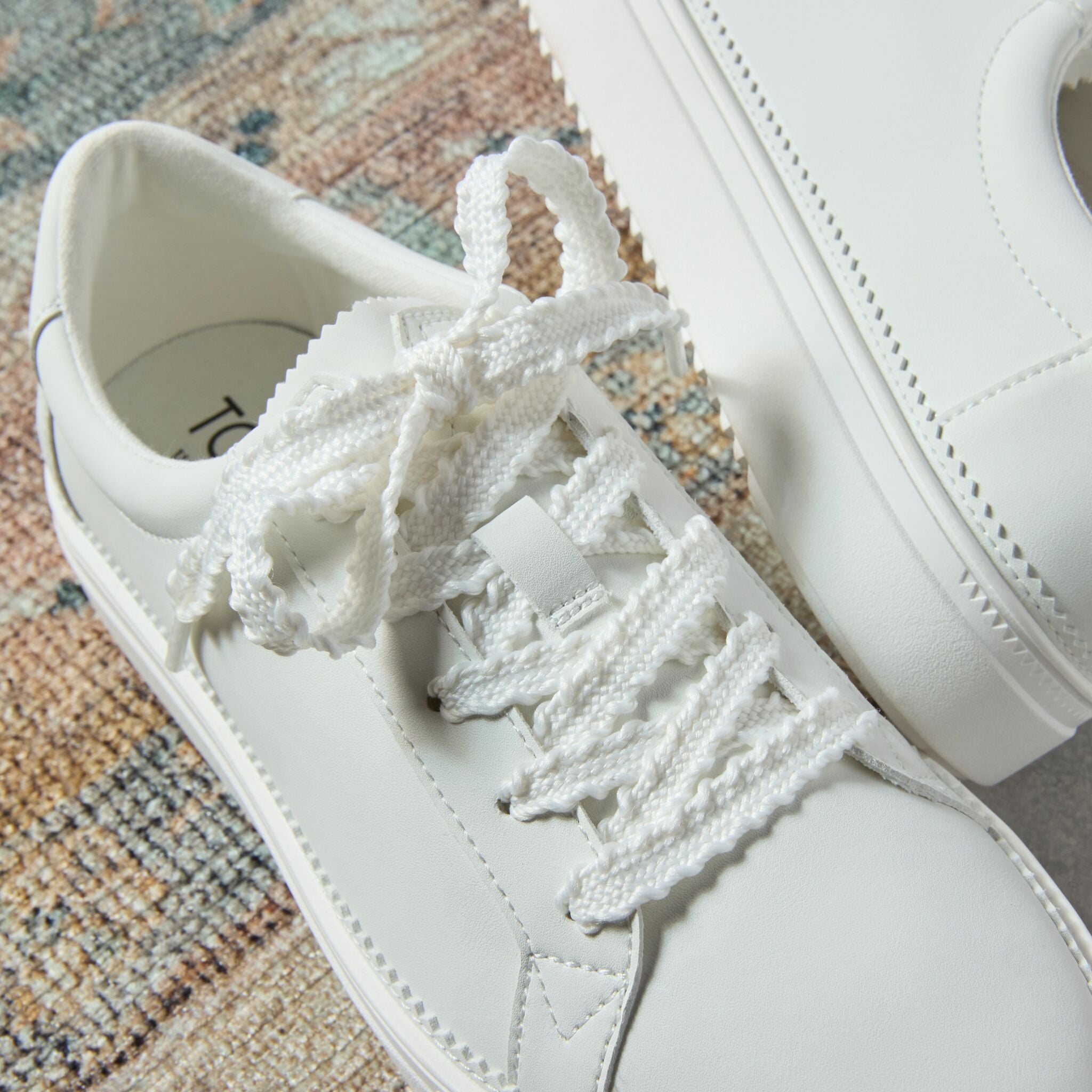 Laydown detail image of the white leather Izzy lace up sneaker